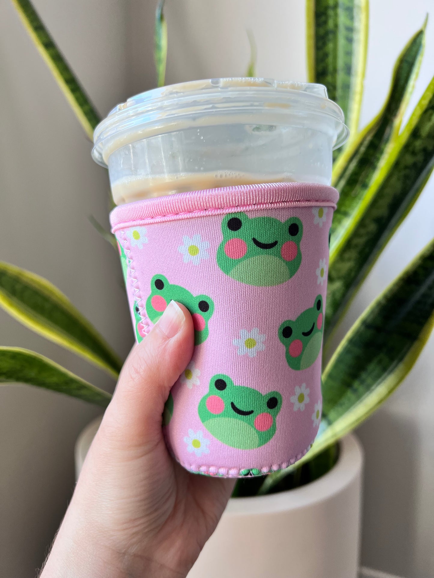 Neoprene drink sleeve that’s pink with cute frogs and daises on it