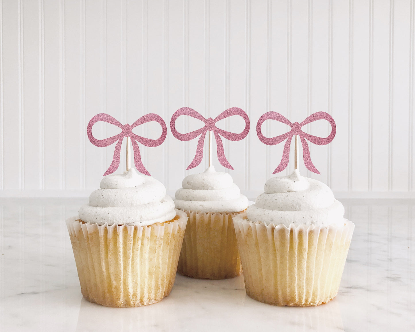 cupcakes with glitter pink bows on top of them