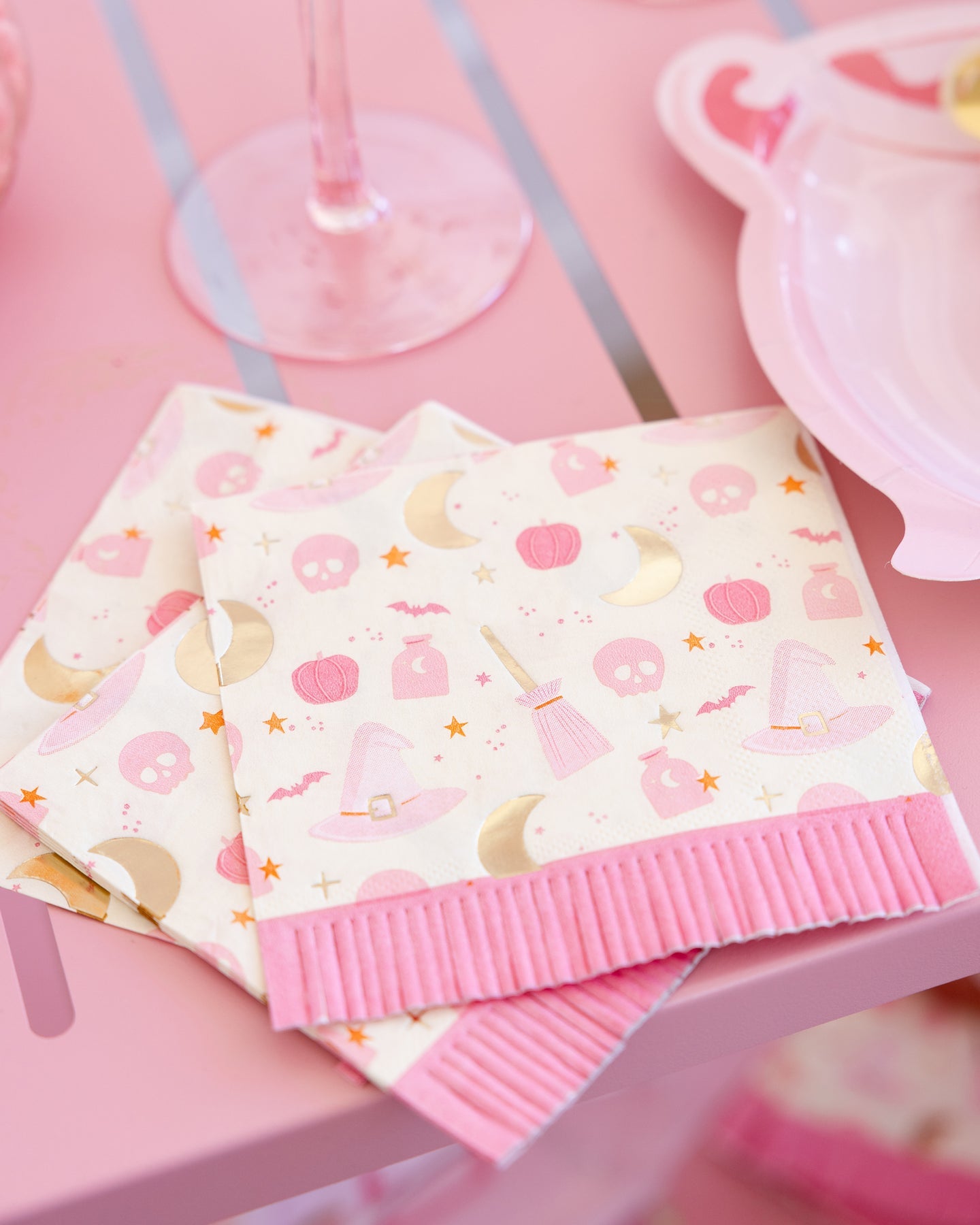 pink hpcus pocus paper napkins with pink fringe and fun halloween shapes sitting on a table