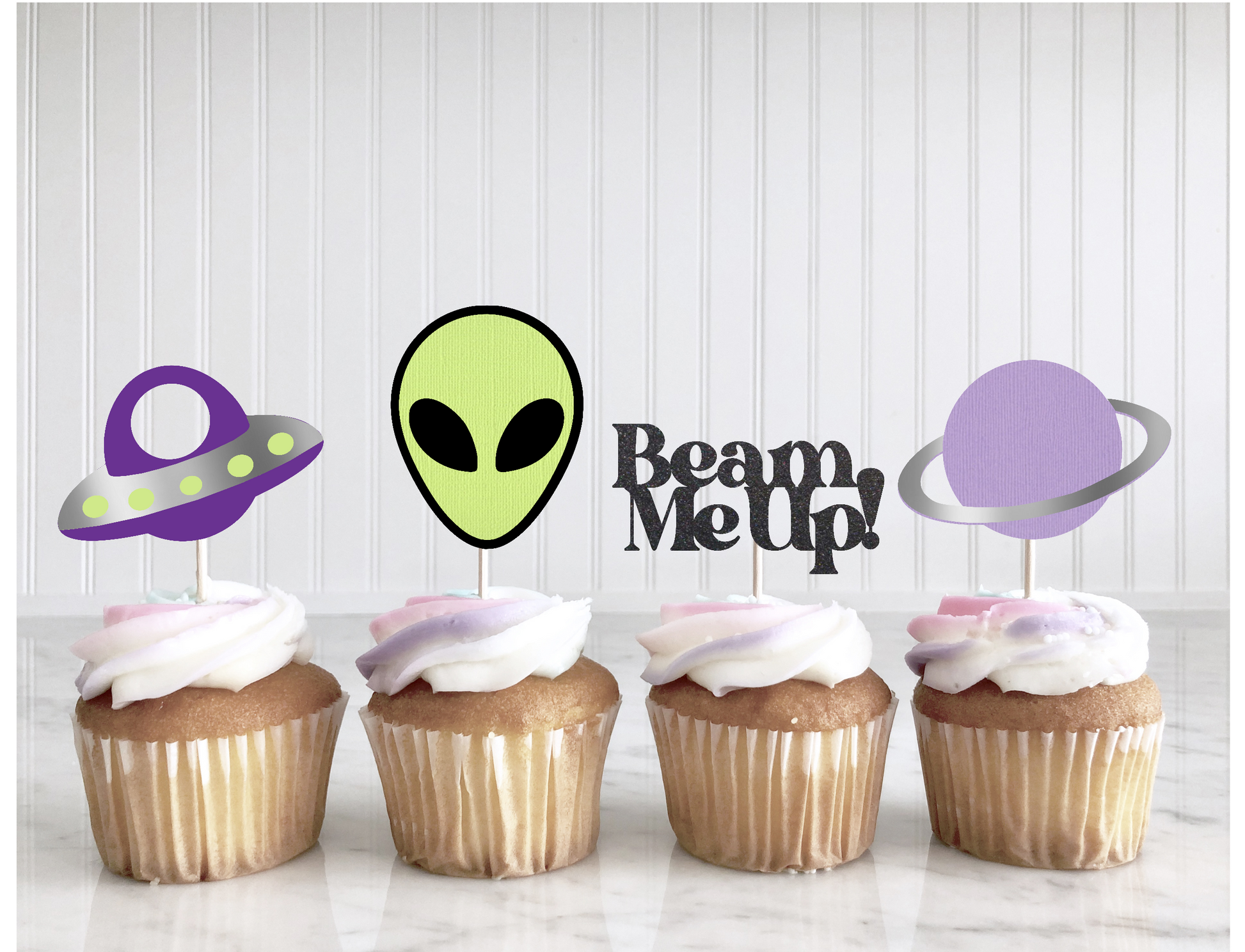 Four cupcakes with space-themed toppers on a white background