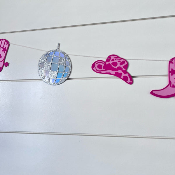 disco cowgirl themed garland with disco balls, pink cowboy boots and pink cowboy hats