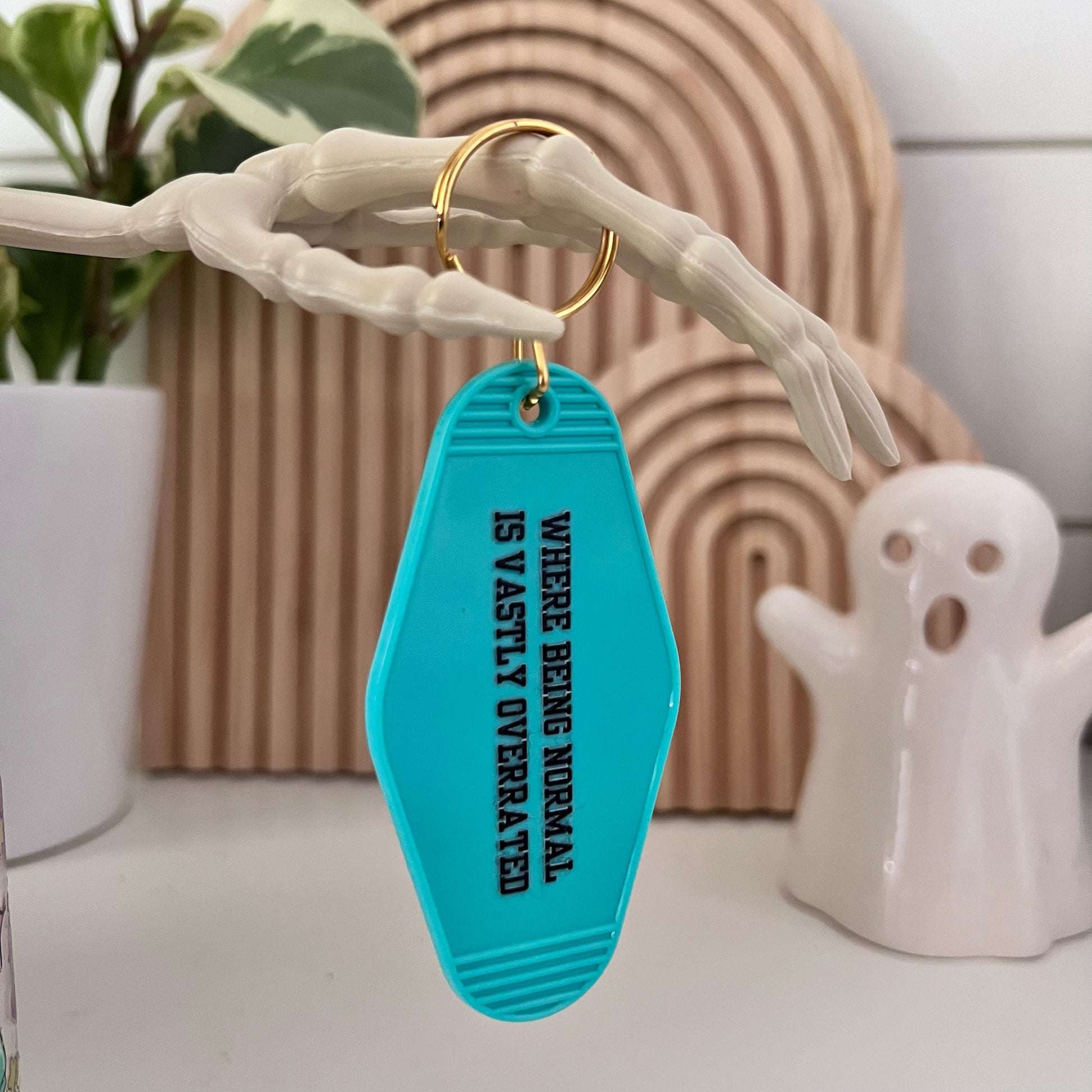 motel keychain with "where being normal is vastly overrated" saying on it
