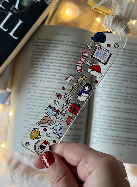 Decorative bookmark with Christmas-themed stickers held over an open book.