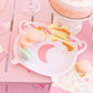 pink cauldron paper plates with a pink moon on front and gold foil bubbles on a table with macarons on top