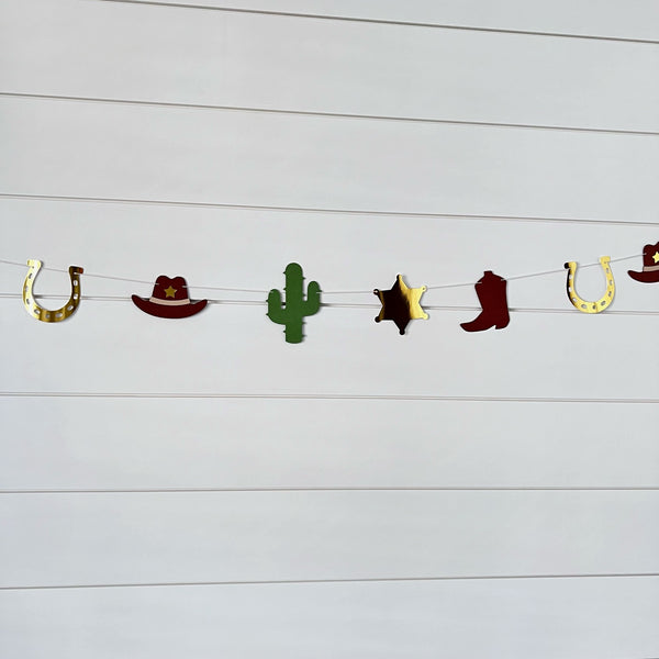 cowboy themed garland with cowboy hats, cacti, gold foil sheriff badge and brown cowboy boots