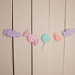 assorted pastel candies strung on white twine hanging against wall 