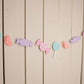 assorted pastel candies strung on white twine hanging against wall 
