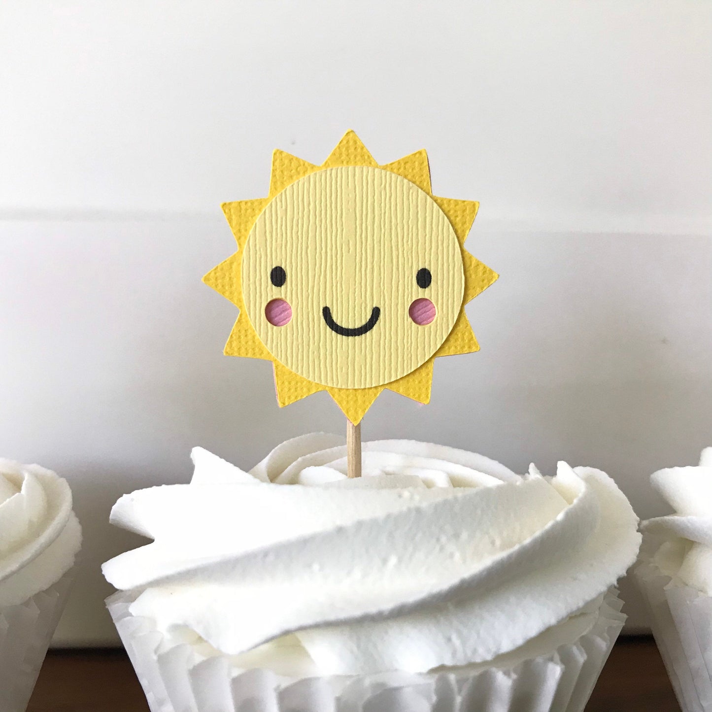 closeup of sunshine cupcake topper that have pink cheeks